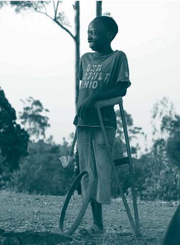 • Niño africano, de pie sosteniéndose en sus muletas y sonriendo | Tomada de: Pxfuel