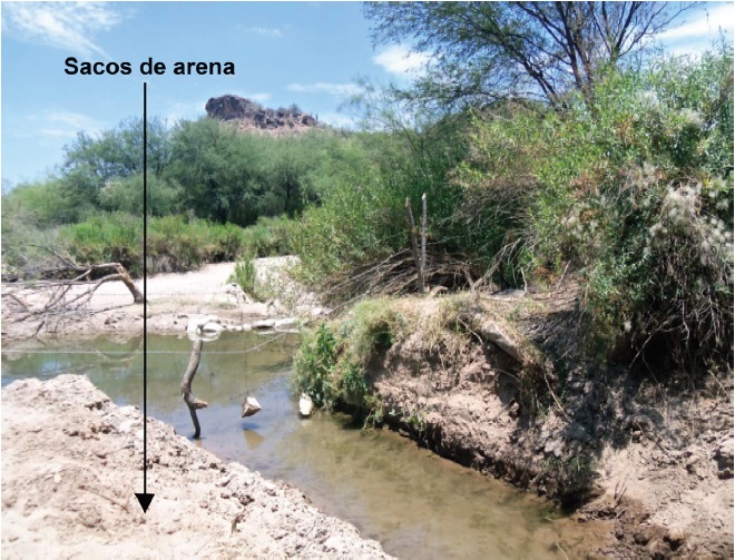 Barrera de sacos de arena que desv&iacute;an el agua del r&iacute;o hacia el canal.