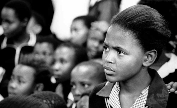 Ni&ntilde;os de la escuela primaria Paul Mosaka observan la obra Lest Talk About It, que es parte de una campa&ntilde;a de concientizaci&oacute;n y prevenci&oacute;n del VIH/Sida, presentada por el grupo Soweto Youth Drama Society. Soweto, Sud&aacute;frica, 11 de septiembre de 2001.