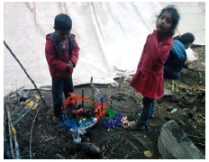 Dos niños realizan casas tradicionales en miniatura en el taller.