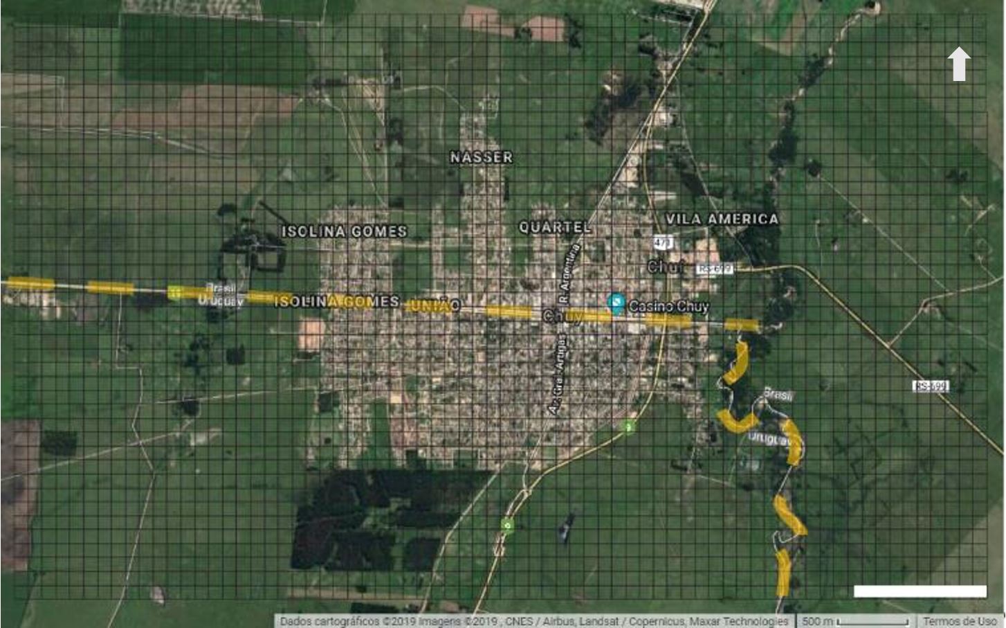 - Imagem de satélite mostrando o local de trabalho, com as cidades do Chuí (RS) acima e Chuy (UY) abaixo da linha tracejada amarela; em preto aparece o grid de 2.800 células de 100m. Fonte na plataforma do PeopleGrid (2019). Dos autores (2019).