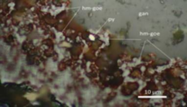 Cristal euhedral de pirita (py) conjuntamente con entrecrecimientos anhedrales de hematita-goethita (hm–goe) diseminados en la ganga (gan). Muestra S-2