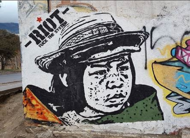 Mural que incita en inglés a un motín contra “el sistema”. Artista anónimo. 