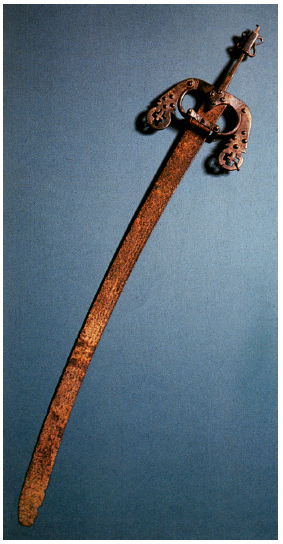 −Sword of Status. Kongo Kingdom, 16th - 19th century, iron, height: 55 cm. Ethnological Museum - Staatliche Museen zu Berlin, inv. III C 44945. Photograph from Jill Rosemary Dias. África: nas vésperas do mundo moderno (Lisbon, 1992, p. 141).