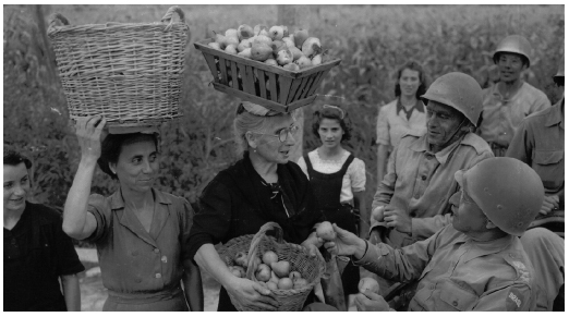 A arte do escambo era uma realidade cotidiana e inescapável na Itália ocupada. Aqui, duas camponesas carregam frutas - peras, ao que parece - e as oferecem ao comandante da FEB, general Mascarenhas de Moraes, em visita ao front. Ele as aceita, presenteando as mulheres com cigarros brasileiros, à guisa de pagamento.