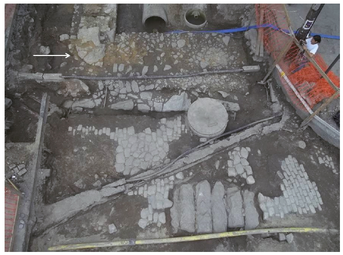 Adjacentes aos antigos cal&ccedil;amentos do Beco da Pedra do Sal, podem ser vistos os alicerces da fachada lateral e dianteira do lote n&ordm; 68, bem como o cunhal curvil&iacute;neo (assinalado com uma seta) que atesta sua localiza&ccedil;&atilde;o em uma esquina, antes da amplia&ccedil;&atilde;o. Foto: Andrea Jundi.