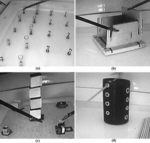 Displacement tests: (a) De1-Cylinders: to order ten cylinders from the smallest to the largest in a board, (b) De2-Boxes: to build two boxes using five wooden components, (c) De3-Tower: to build up a tower made of four cubes and to locate four objects around the tower, and (d) De4-Sticks: to cross a hollow cylinder with eight sticks throughout some predefined holes.