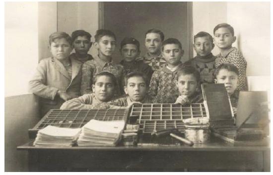 Alumnos de la escuela de Consell en 1934 junto a la imprenta escolar. (DEYÁ, 1941, p. 14).