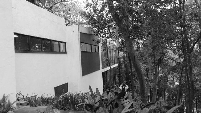 Fachada lateral da Casa de vidro, na qual se v, em primeiro plano, o volume apoiado sobre o terreno (cozinha) e, em segundo, o volume sobre pilotis