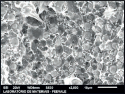 Micrografia do corpo de prova injetado, região clara: sistema ligante, região escura: pós constituintes. Aumento: 2000x. Escala: 10 µm.