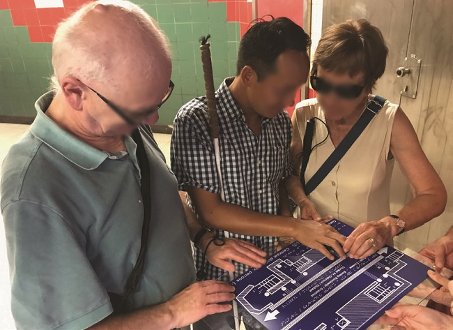 (a) participantes caminham pelo corredor de acesso à estação de metrô; (b) participantes encontram primeira guia tátil no piso; (c) participante utiliza primeiro mapa tátil de acesso ao sistema.