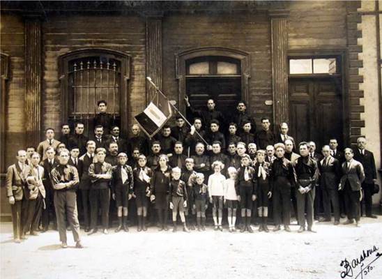 El fascio de Iquique, sin fecha, posiblemente d&eacute;cada de 1930. Fotograf&iacute;a propiedad de la familia Canessa, facilitada para esta investigaci&oacute;n por Vittorio Canessa, nieto de Humberto Canessa, miembro del fascio. Destaca la bandera fascista, los hombres con camisas negras, ni&ntilde;os balilla y j&oacute;venes avanguardistas.