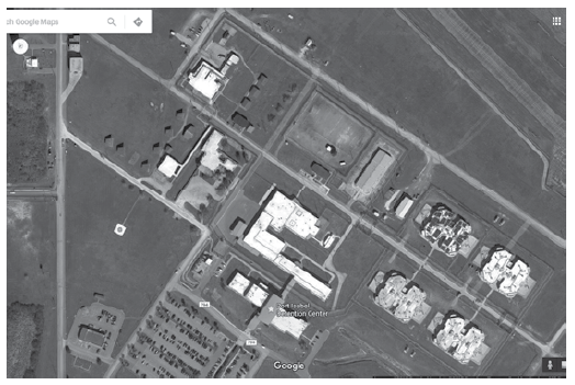 Nuevo centro de procesamiento en el PIDC. Todas las renovaciones del PIDC se completaron en 2007 con la adición del gran edificio central de varias alas, que reemplazó el antiguo Centro de Detención. Lo más probable es que en ese momento se trasladaran el procesamiento y la detención del edificio de procesamiento de menor tamaño (centro a la izquierda con el techo blanco y área levemente modificada) a este edificio. Foto cortesía de Google Maps, 2016.