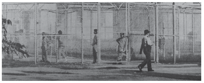 Cercado y seguridad, después de 1980. Los detenidos a lo largo del corredor en exteriores seguro entre las zonas aseguradas del PIDC. Crédito de la fotografía: Austin Holiday (Holiday, 1991).