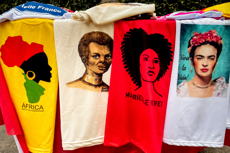 Apropriação da imagem criada por Yhuri Cruz, sem a máscara e identificada, na legenda da camiseta, como Escrava Anastácia, incorporada à iconografia política que circula no comércio de camisetas no Rio de Janeiro.