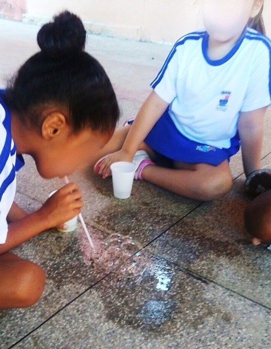 Criança fazendo  cacho de uva com bolhas de sabão