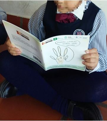 Taller cuenta cuentos y juegos. Fotograf&iacute;a de estudiante de la escuela privada utilizando el libro infantil: Manos limpias. Ni&ntilde;os m&aacute;s sanos (Oberto et al., 2016).