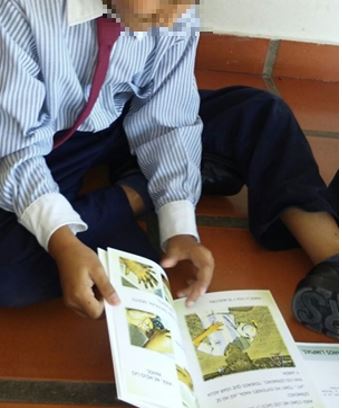 Taller cuenta cuentos y juegos. Fotograf&iacute;a de estudiante de la escuela privada utilizando el libro infantil: Manos limpias. Ni&ntilde;os m&aacute;s sanos (Oberto et al., 2016).