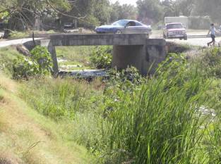 View of the stream and the bridge to access the colonia