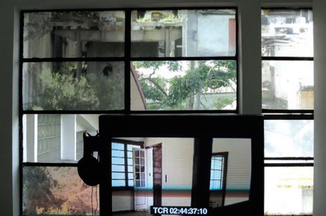 Imagen de la
videoinstalaci&oacute;n La Siberia: recuerda al
olvidar. Pantalla con material de archivo sobre un mosaico de ventanas,
algunas con transparencias impresas de im&aacute;genes de la ruina.