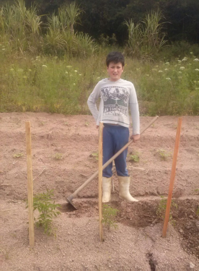 Filho de uma famlia de produtores agroecolgicos que participam da feira Criana comeando sua horta de tomates