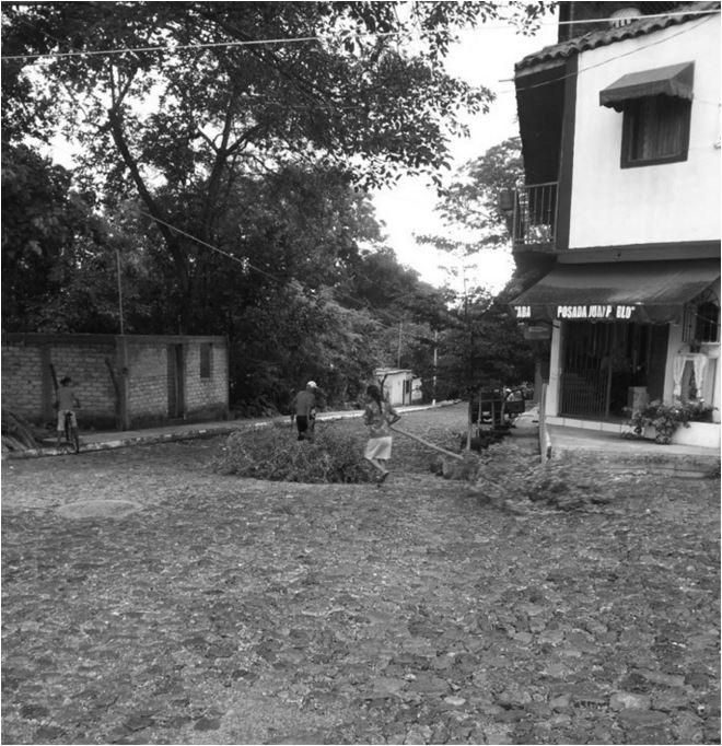 Hombre
y mujer arrastran ramas bajo la lluvia. La mujer ayuda al hombre