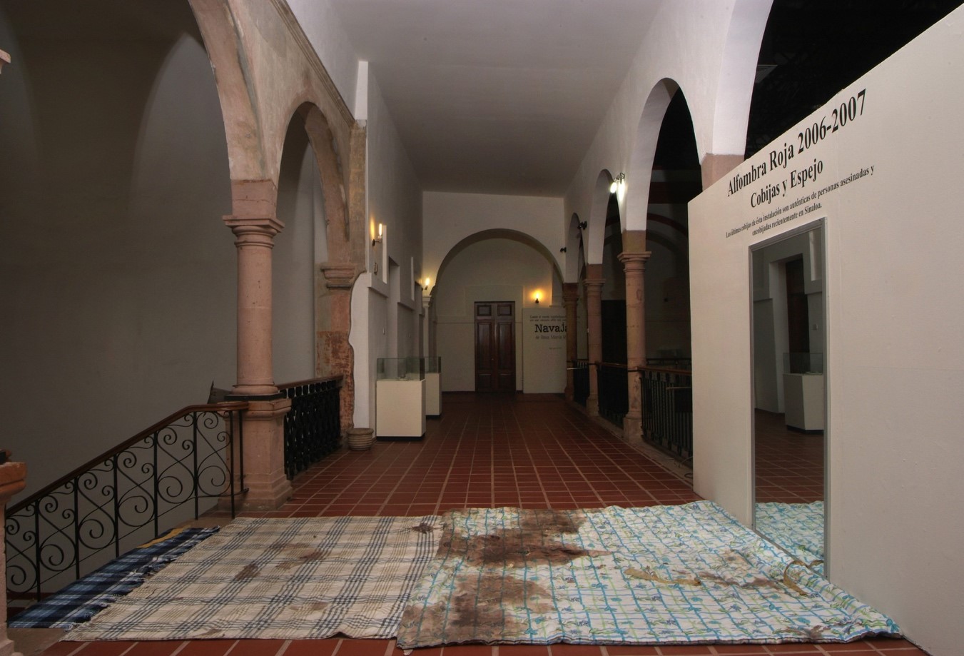 Alfombra Roja, del Proyecto Navajas, de Rosa María Robles. Museo de Arte de Sinaloa, Culiacán, 2007. Primera versión de esta instalación en la que se utilizaron cobijas auténticas de personas asesinadas en el estado de Sinaloa y que fueron retiradas de la exposición por la PGJS, la noche del 20 de junio de 2007.