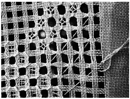 Calado en proceso. Tela parcialmente destruida por el deshilado y la producción de una puntada llamada punto espíritu