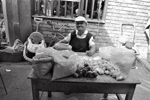 Vendedora de aliños. En el mercado se puede negociar al detal, de manera que se pueden encontrar productos en medidas mínimas empacadas en papel, hojas de plantas y plástico, y en medidas como tarros, botellas, puchos, cuartas, sobres y papeletas. En el caso de los aliños o las especias, para cada presupuesto hay una cantidad de producto que el cliente puede llevar, para nunca irse con las manos vacías.