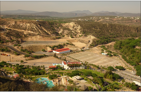 Vistas hacia el oeste sobre el «Balneario El Géiser», complejo turístico desarrollado a partir de 1985 en lo que fuera la planta geotermoeléctrica de Pathé -la primera del continente americano (operativa entre 1959 y 1972)-. El complejo se ubica en un surco tectónico de aproximadamente medio km de ancho y dirección N-S, producido por la Falla de Pathé, a la cual se asocia el graben de San Francisco (Carrillo Martínez, 1998), en su intersección con la Falla Moctezuma (SGM, 2007), de dirección WSW-ENE y asociada al semigraben de Aljibes (Suter et al., 1995). En segundo plano, al centro de la fotografía, se observa en tonos amarillentos el escarpe de la Falla de Pathé.