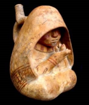 Botella Moche I-II representando a una curandera con manto en forma de pallar, que lleva en sus manos semillas de alguna planta sagrada