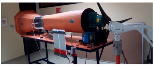 Montaje del túnel de viento sobre la mesa de trabajo (equipo naranja) y turbina eólica Air X (carcaza blanca, con aspas negras).