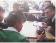 Estudiantes trabajando en grupo en torno a la experiencia de hacer mover la llama de una vela como efecto de la producci&oacute;n de sonidos con diferente frecuencia e intensidad.