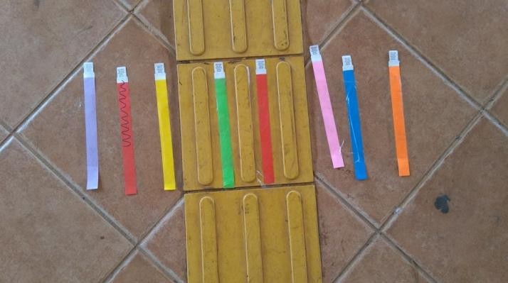 Pulseiras coloridas dispostas ao longo do piso t�til da Escola