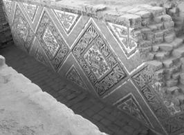 Patio 1 o de los Rombos en la Huaca de la Luna (fotografía del autor). Se observa el rostro de Ai Apaec, el dios degollador, rodeado de serpientes esquemáticas o estilizadas.