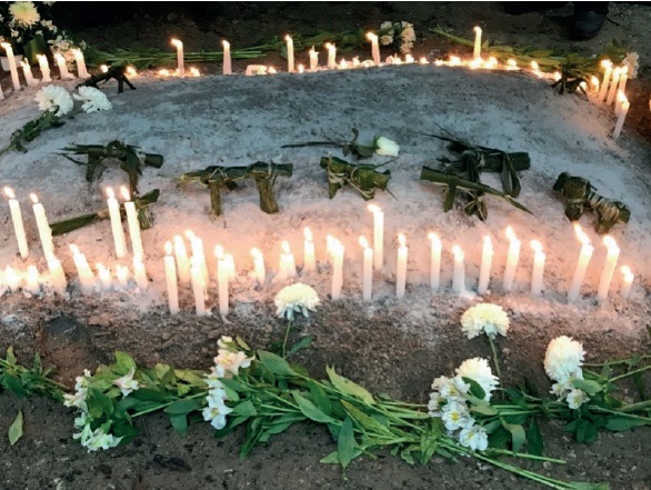 Perritos hechos con hoja de palma y velas depositados en una tumba durante un funeral, Nahá, 2018