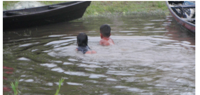 Crian&ccedil;as brincando na canoa e a m&atilde;e de uma delas acompanhando