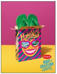 Campaign with sandals inside a box containing an illustration on the front and the word &lsquo;Happiness&rsquo; with the face of a smiling person.