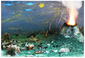 Maqueta de volc&aacute;n realizada por uno de los autores (J.V.A.) y &laquo;erupci&oacute;n&raquo; provocada por la reacci&oacute;n redox discutida en el texto. Esta experiencia se lleva a cabo en vitrina de gases de laboratorio.